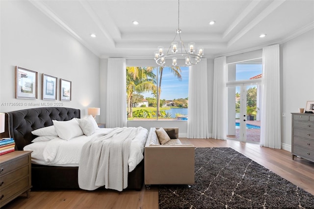 bedroom featuring a raised ceiling, a notable chandelier, access to exterior, and light wood-type flooring