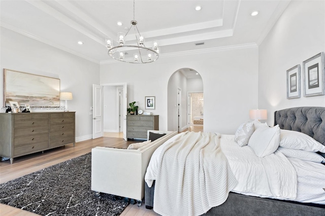 bedroom with crown molding, hardwood / wood-style floors, a high ceiling, a notable chandelier, and a raised ceiling