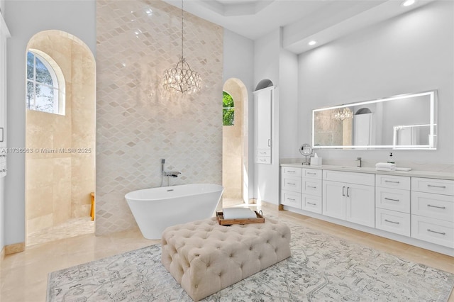 bathroom with vanity, a bathtub, tile walls, and a notable chandelier