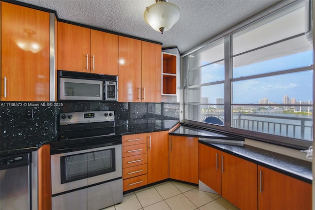 kitchen featuring dark stone countertops, light tile patterned floors, decorative backsplash, and stainless steel appliances