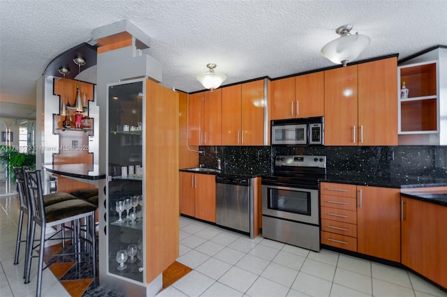 kitchen with light tile patterned flooring, sink, tasteful backsplash, a textured ceiling, and stainless steel appliances