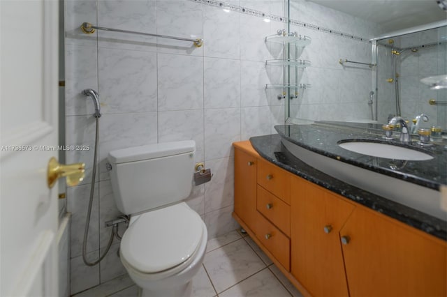 bathroom with vanity, a shower, tile walls, and toilet