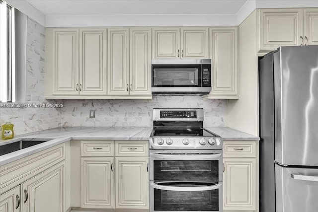 kitchen with stainless steel appliances, decorative backsplash, and cream cabinetry