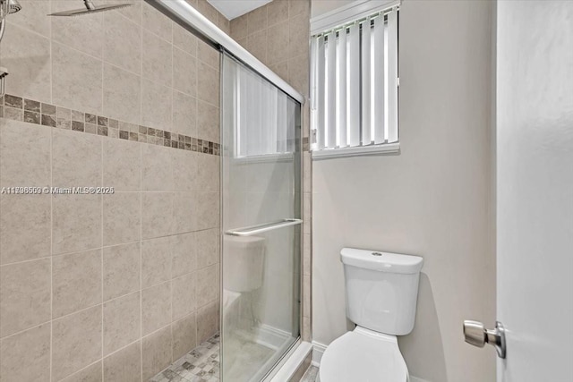 bathroom with a shower with shower door and toilet