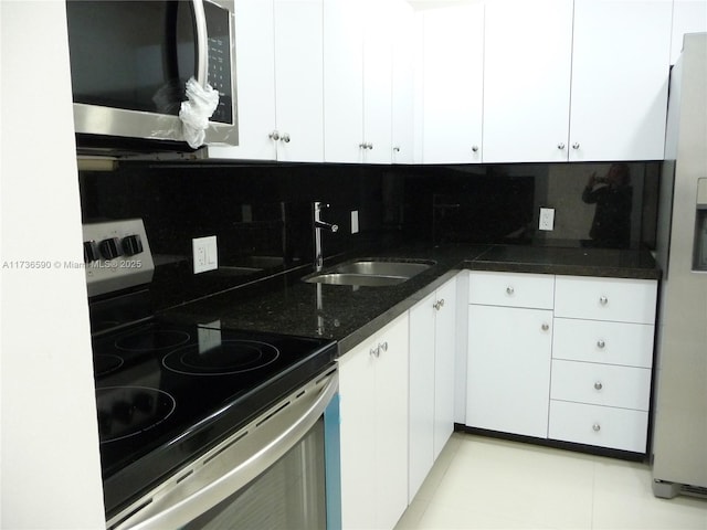 kitchen with appliances with stainless steel finishes, sink, white cabinets, and backsplash