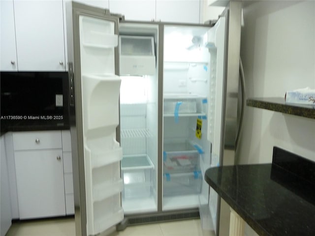 interior space featuring white cabinetry, dark stone counters, and stainless steel fridge