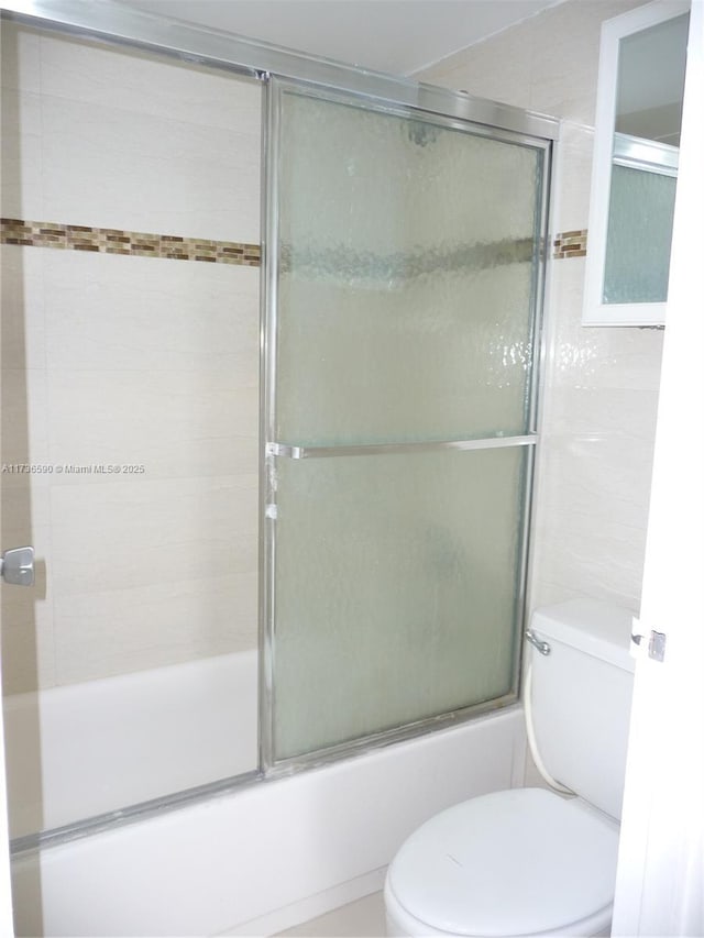 bathroom featuring combined bath / shower with glass door and toilet