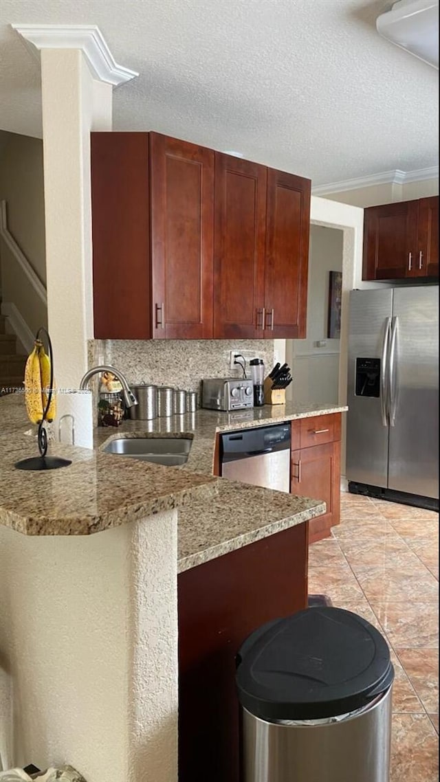 kitchen with sink, stainless steel appliances, light stone countertops, decorative backsplash, and kitchen peninsula