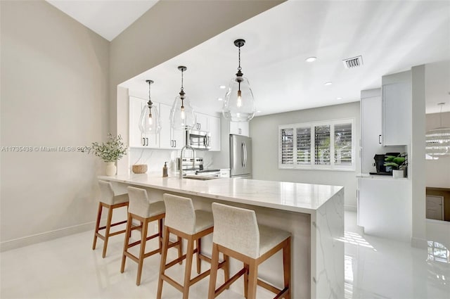 kitchen featuring white cabinetry, stainless steel appliances, decorative light fixtures, and kitchen peninsula