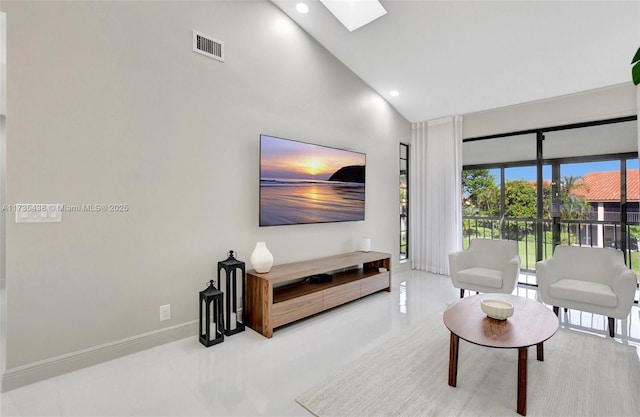 living room with a skylight and high vaulted ceiling