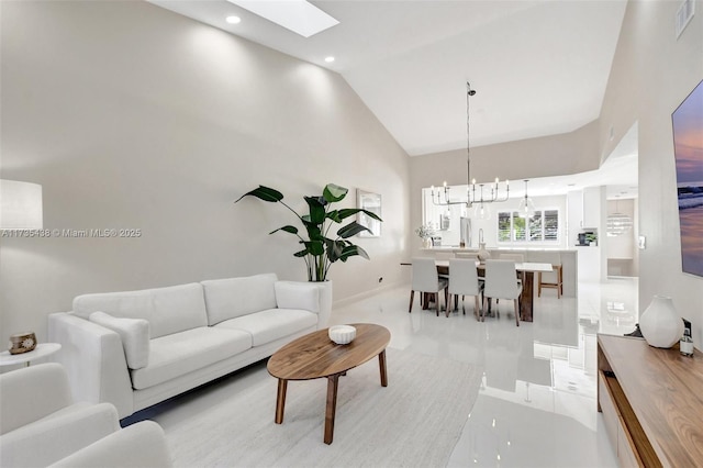 living room with a notable chandelier, a skylight, and high vaulted ceiling