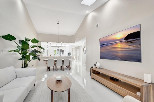 living room with high vaulted ceiling, an inviting chandelier, and a skylight