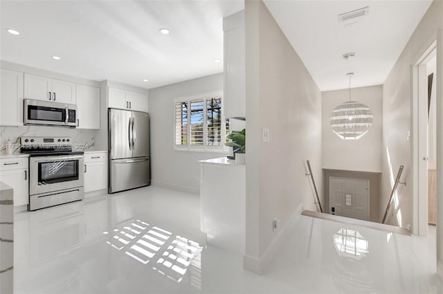 kitchen featuring an inviting chandelier, backsplash, stainless steel appliances, white cabinets, and decorative light fixtures