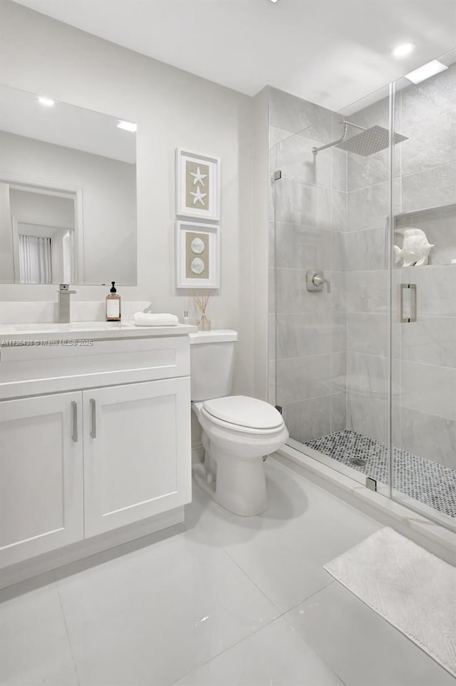 bathroom with vanity, a shower with door, and toilet