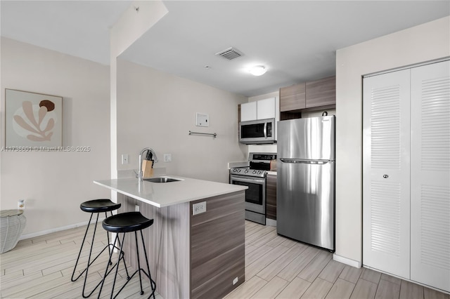 kitchen with sink, stainless steel appliances, kitchen peninsula, and a kitchen bar