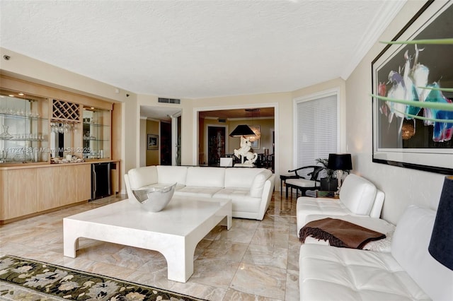 living room featuring wet bar, marble finish floor, visible vents, and a textured ceiling