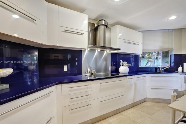 kitchen with light tile patterned floors, black electric cooktop, backsplash, white cabinets, and wall chimney range hood