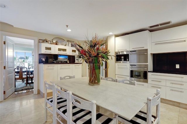 kitchen featuring white cabinetry, light tile patterned flooring, and double oven