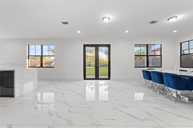 unfurnished living room with a wealth of natural light and french doors