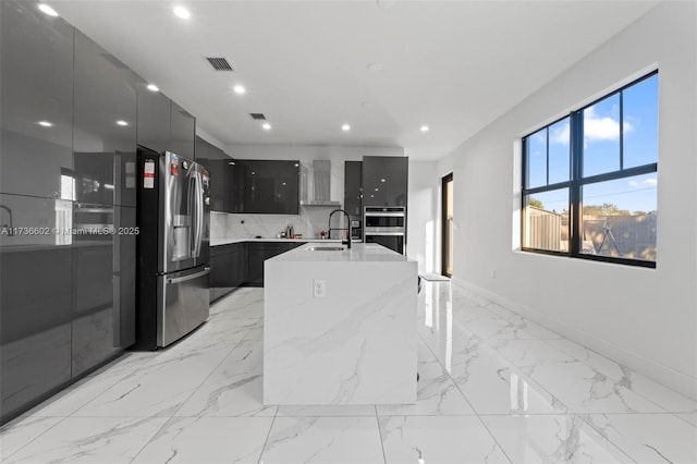 kitchen featuring sink, a breakfast bar area, a kitchen island with sink, stainless steel appliances, and light stone countertops