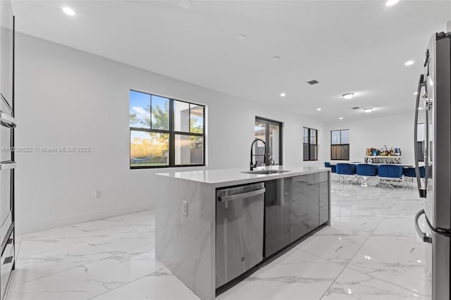 kitchen with an island with sink, appliances with stainless steel finishes, and sink