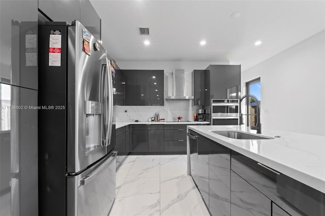 kitchen with tasteful backsplash, wall chimney exhaust hood, stainless steel appliances, and sink