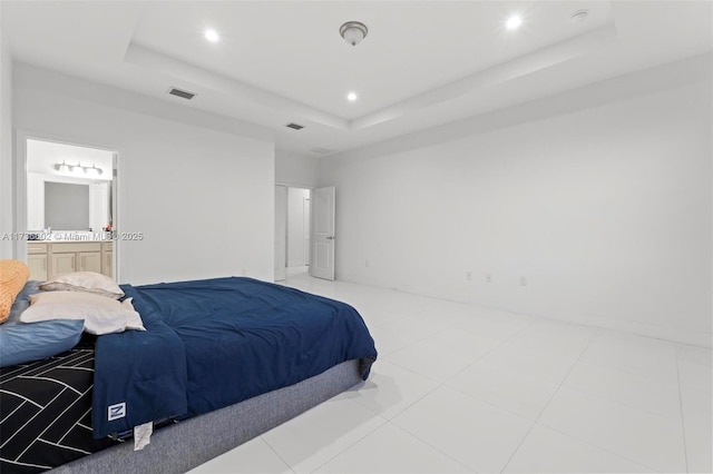 tiled bedroom featuring a raised ceiling and ensuite bathroom