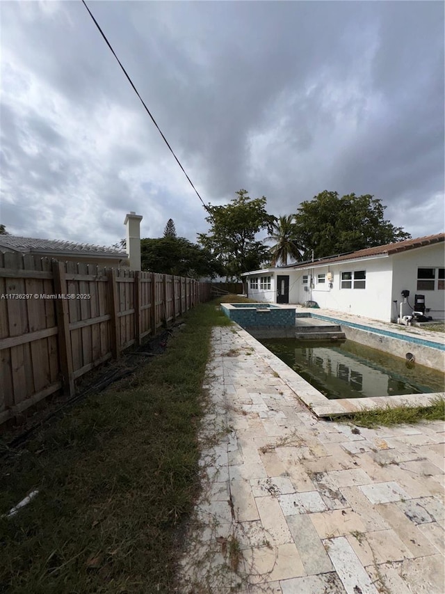 view of yard featuring a swimming pool with hot tub and a patio area