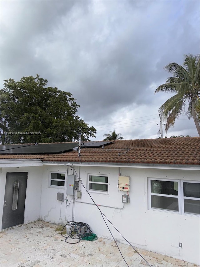 view of property exterior with a patio and solar panels