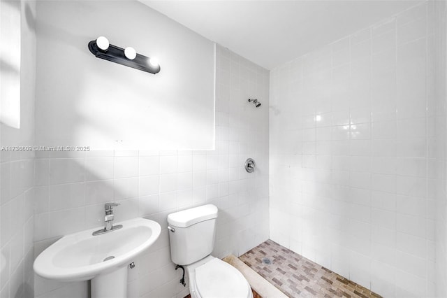 bathroom featuring tile walls, sink, toilet, and tiled shower