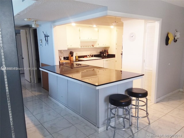 kitchen featuring dishwasher, dark countertops, a breakfast bar, marble finish floor, and a sink