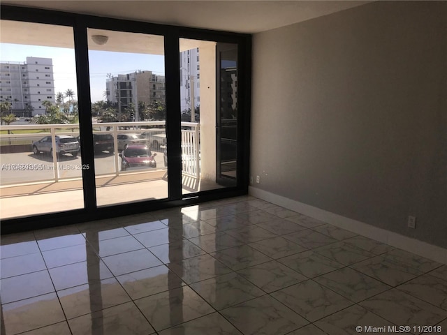 empty room with baseboards, a wall of windows, and a city view