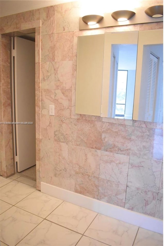 empty room featuring marble finish floor and tile walls