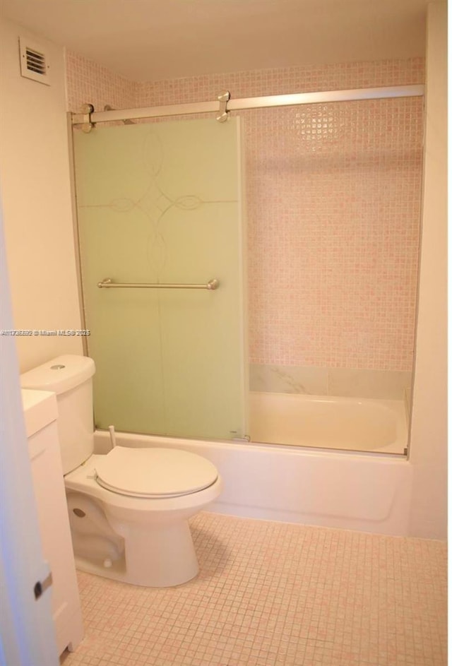 bathroom featuring visible vents, toilet, enclosed tub / shower combo, vanity, and tile patterned flooring