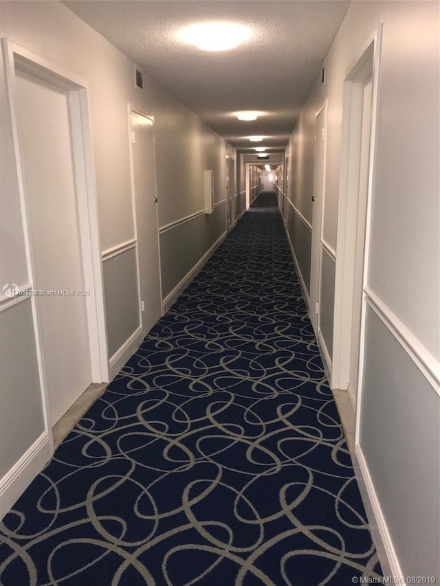 hall with carpet flooring and a textured ceiling