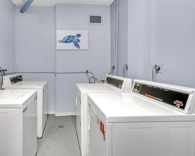 common laundry area with separate washer and dryer, visible vents, and baseboards