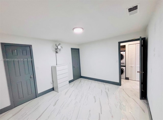 unfurnished room featuring stacked washer and dryer