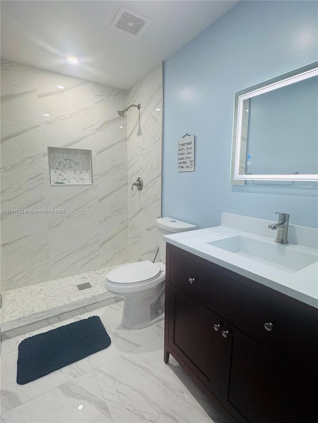 bathroom with vanity, a tile shower, and toilet