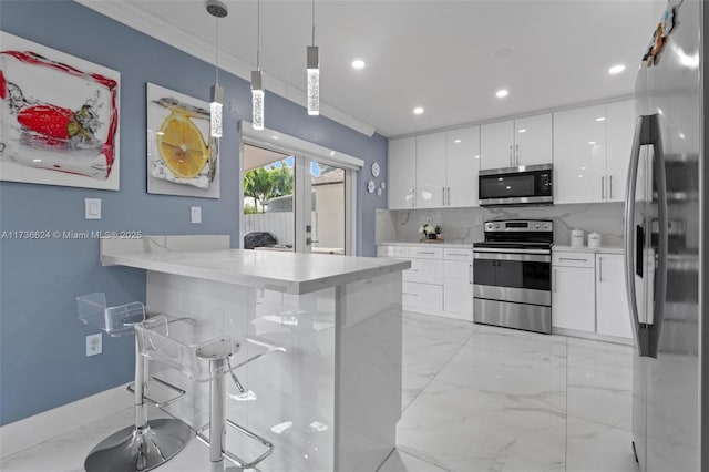 kitchen with white cabinetry, a kitchen bar, hanging light fixtures, and appliances with stainless steel finishes