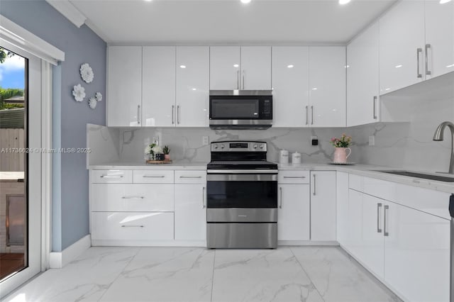 kitchen with sink, backsplash, white cabinets, and appliances with stainless steel finishes