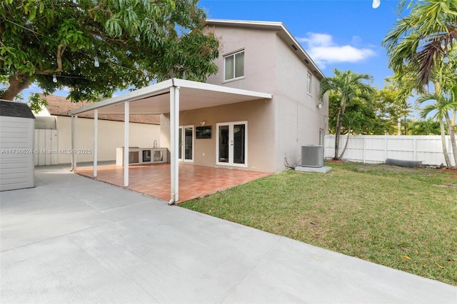 rear view of house with a yard, central AC, and a patio area