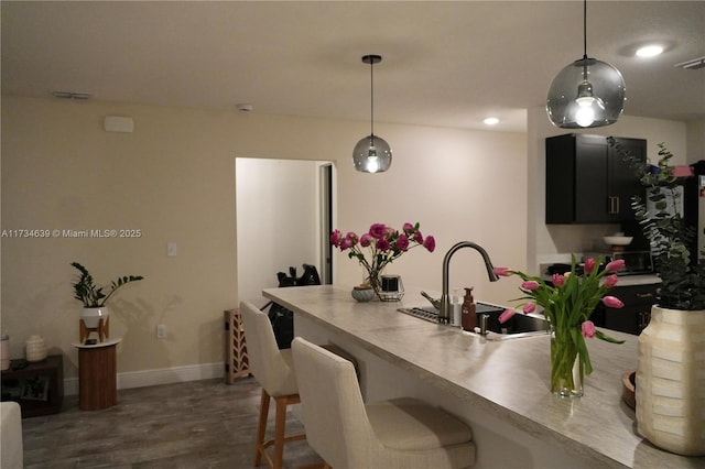 kitchen with pendant lighting, sink, dark hardwood / wood-style flooring, and a kitchen breakfast bar