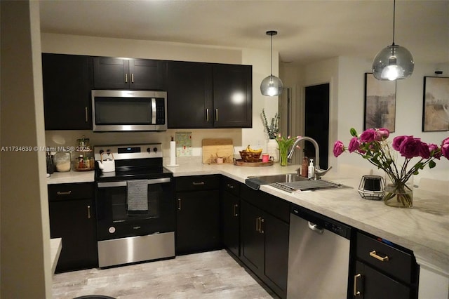 kitchen with dark cabinetry, light countertops, a sink, and appliances with stainless steel finishes
