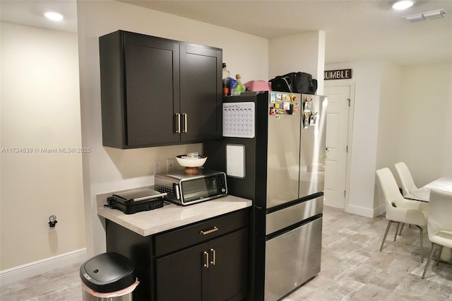 kitchen with visible vents, light countertops, freestanding refrigerator, and light wood-style floors