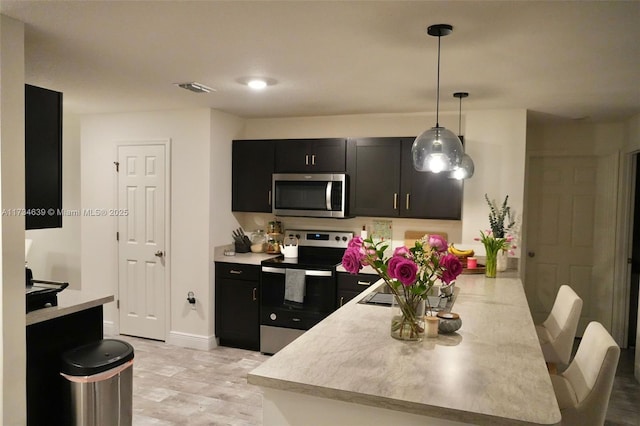 kitchen with hanging light fixtures, kitchen peninsula, and appliances with stainless steel finishes