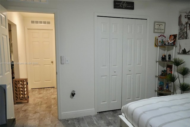bedroom featuring a closet, wood finished floors, visible vents, and baseboards