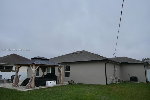 rear view of property with a gazebo, a patio, central AC, and a lawn