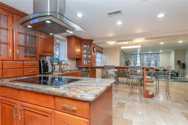 kitchen featuring sink, island range hood, black electric cooktop, light stone countertops, and backsplash