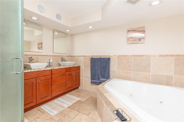 bathroom with tile walls, vanity, and tiled bath