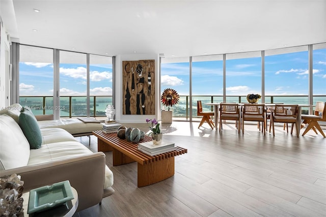 living room with a water view, a wall of windows, and light hardwood / wood-style flooring